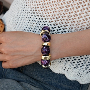 Close-up of bohemian beaded bracelet with purple marble beads and gold hollow metal links
