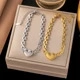 Détail de bracelets cœur en titane argent et or sur un plateau en velours beige