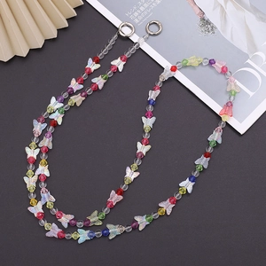 Colorful butterfly beaded crossbody phone strap with metallic round buckles on black surface