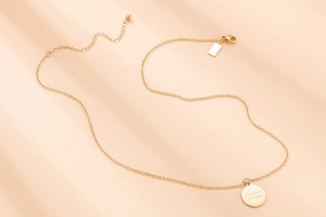 Détail du collier en acier doré avec pendentif gravé One In A Million poli