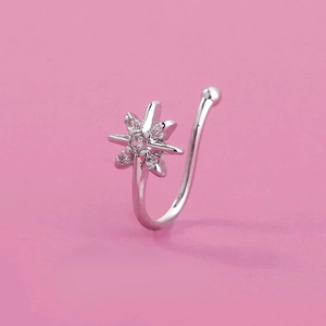 Macro view of silver star nose ring with clear zircon inlay on pink background