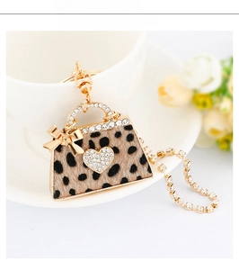 Detail of leopard print handbag keychain with golden heart rhinestone and bow accessory