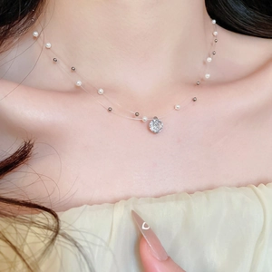Detail of double-layer necklace with zircon pendant and pearls on clear fishing line