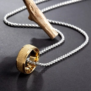 Titanstahl-Pärchenhalskette mit goldener Ring-Anhänger auf schwarzem Hintergrund