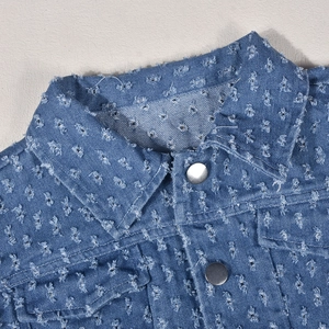 Close-up of blue denim vest with distressed flower texture and silver metal buttons