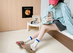 Detailed view of dopamine-colored mesh socks worn with thick-sole brown slippers