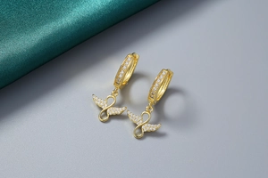 Détail de boucles d'oreilles ailes d'ange infini dorées 18K avec zircons blancs