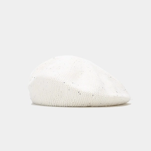 Gros plan du béret en tricot blanc orné de paillettes argentées et texture en laine