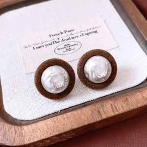 Close-up of vintage brown flocking earrings with pearl inlay on a wooden display tray