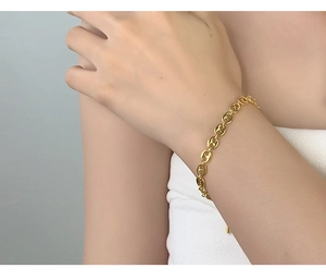 Close-up of golden coffee bean link bracelet worn on wrist for a minimalist style