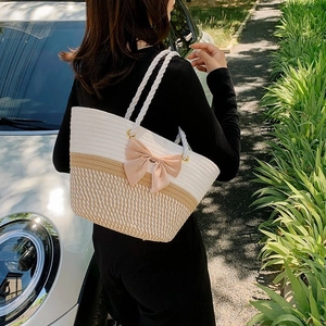 Women's handmade floral woven straw tote bag with large pink bow and beige khaki tones