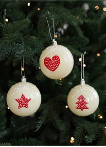 Detailed view of beige Christmas balls with red star and heart patterns on a tree