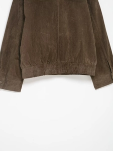 Détail de veste en daim marron montrant l'ourlet élastique et les poignets boutonnés