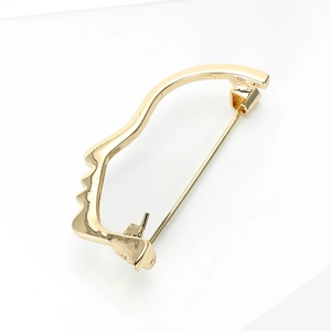 Macro shot of minimalist gold abstract face silhouette brooch with smooth metallic finish