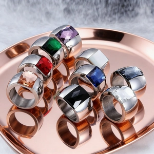Macro view of wide stainless steel rings featuring multi-colored square crystals on tray