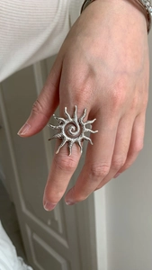 Chunky silver sunburst ring with hammered texture and spiral center on index finger