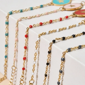 Golden stainless steel star bracelets with colorful enamel charms on a white display
