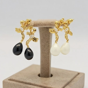 Detail of bow-knot teardrop earrings in black and white with gold-plated zircon setting