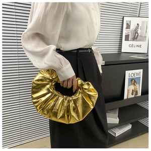 Details der goldenen Handtasche mit Falten-Effekt und kreisförmigem Metallgriff