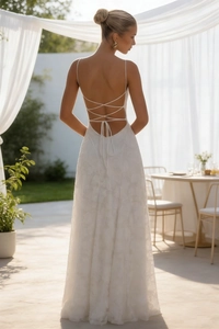 Close-up of white lace wedding dress featuring backless crisscross strap design details
