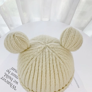 Detail of cream knit beanie featuring cute bear ears and thick ribbed texture fabric