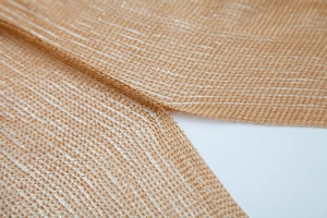 Macro shot of gold metallic mesh fabric with sheer texture and shimmering fringe detail
