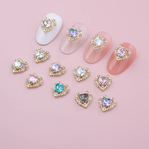 Detail view of heart-shaped nail charms with colored gems and gold-plated borders