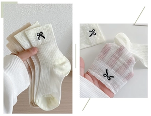 Detail of sheer mesh ballet socks with black bow embroidery and breathable texture