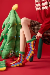 Close-up of soft coral fleece Christmas socks with colorful argyle pattern and festive decor