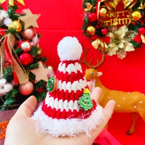 Detail of red and white striped hand-knitted Christmas hat for pets with pom-pom