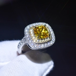 Macro shot of square cut yellow moissanite ring with halo setting on a black background