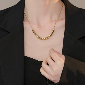 Minimalist gold ball bead necklace for women styled with a black suit for a modern look