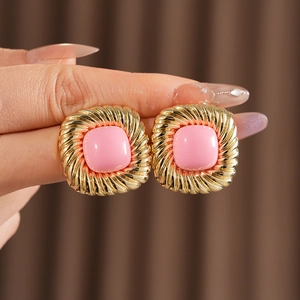Details von quadratischen Vintage-Goldohrringen mit rosa Edelsteinen in der Hand