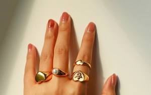 Close-up of 18k gold plated stainless steel rings featuring heart and pearl details