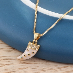 Macro shot of gold horn pendant with sparkling zircon set on a blue ceramic dish edge