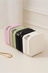 Stack of colorful PU leather travel jewelry boxes in pink, green, black and white