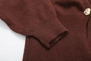Close-up of ribbed cuffs and champagne gold metal button on brown knit cardigan