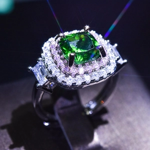 Macro shot of princess cut green gemstone ring with pink and white halo stones