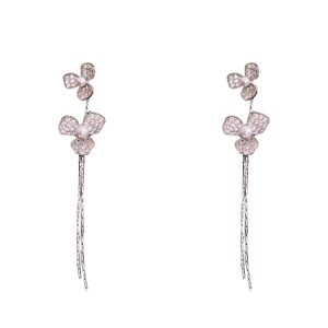 Boucles d'oreilles fleurs argentées avec pompons, zircons et perles sur fond blanc