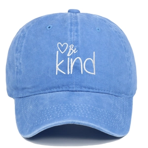 Close-up of Be Kind white embroidery and heart icon on light blue washed cotton cap