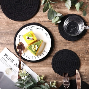 Close-up of black round woven cotton heat-resistant coasters on a wooden table set