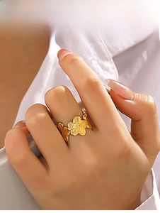 Detail of gold floral ring with brushed petal texture on a hand-worn model