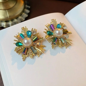 Vintage gold floral stud earrings with white pearl and multicolored crystals on a book