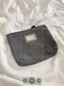 Detail of herringbone plaid makeup bag with Pleasant Time label on a white fabric background