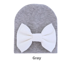 Detail of grey knitted baby hat with a large white bow, soft cotton fabric for infants