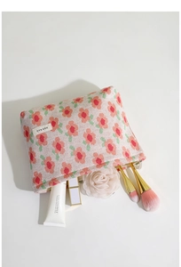 Detail of floral knit makeup bag showing pink flower patterns and inner storage capacity