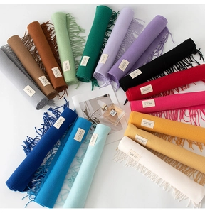 Vista piatta di sciarpe colorate a tinta unita effetto cashmere con frange ed etichette