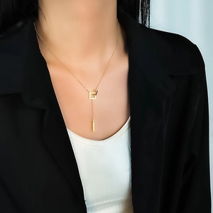 Minimalist gold Y-shaped interlocking necklace worn by model over a white top and black blazer