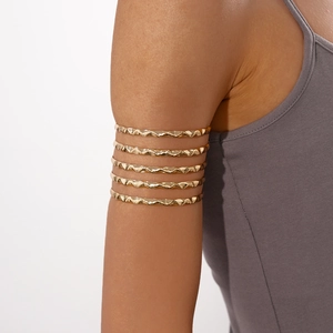 Detailed view of a gold-plated multi-layer pleated wavy arm cuff on a model arm