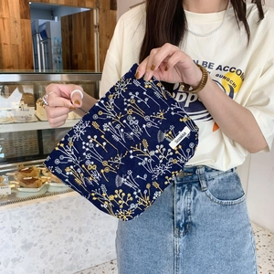 Navy blue floral embroidered makeup bag with yellow and white flowers and woven label